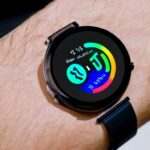 Translucent smartwatch on a minimalist wrist, matte black band, crystal‑clear display, floating holographic interface with crisp icons and data streams, illuminated by subtle blue light, showcasing sustainable, energy‑harvesting wearable design.