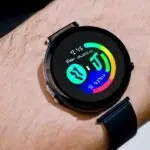 Translucent smartwatch on a minimalist wrist, matte black band, crystal‑clear display, floating holographic interface with crisp icons and data streams, illuminated by subtle blue light, showcasing sustainable, energy‑harvesting wearable design.