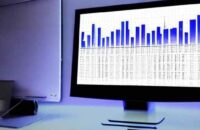 A dimly lit office monitor displays a complex Excel spreadsheet with highlighted financial data cells, illustrating a critical security vulnerability where legacy files interact unexpectedly with modern AI agents.