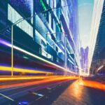 A futuristic twilight metropolis where glowing fiber optic cables weave through skyscrapers, symbolizing AI as the essential infrastructure powering modern urban life.