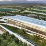 A photorealistic wide shot of a modern technology campus under construction in rural West Virginia, featuring sleek glass buildings surrounded by green fields with cinematic golden hour lighting.
