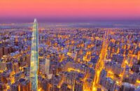 A twilight skyline of a modern Moroccan city blending traditional arches with futuristic glass skyscrapers. Holographic displays float over a bustling digital plaza, symbolizing the convergence of historic heritage and advanced technology.