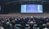 Diverse professionals attend the RSAC 2026 Cybersecurity Conference, listening to a keynote on AI integration strategies. Natural light highlights the audience taking notes as a massive screen displays slides on operating models and reality checks.