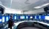 Futuristic security command center with analysts monitoring large curved screens displaying real-time certificate trust metrics and automated renewal dashboards under soft blue lighting, highlighting human oversight in PKI management.