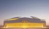 A futuristic datacentre in the Arabian desert at sunset, showcasing resilient, state-led infrastructure with sleek white architecture and glowing blue servers amidst golden sand dunes.