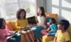 A diverse group of children laughing and playing educational games on tablets while sitting together on a cozy sofa in a sunlit modern living room.