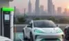 A modern electric vehicle charging station with a high-tech EV parked in a bustling Indian city during a golden hour sunset.