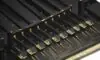 A cinematic close-up of a modern DDR5 RAM stick with a matte black heat spreader and gold-plated pins, highlighting its advanced hardware design.
